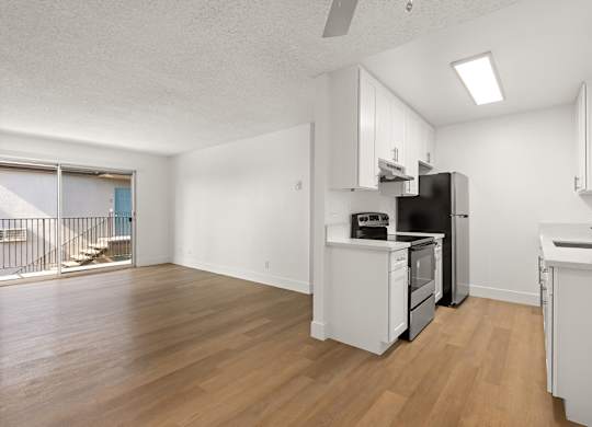 A kitchen with white cabinets and a black fridge.