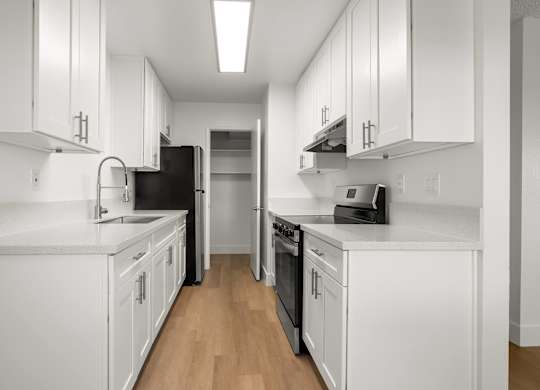 A kitchen with white cabinets and black appliances.