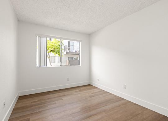 Empty room with a window and wooden flooring.