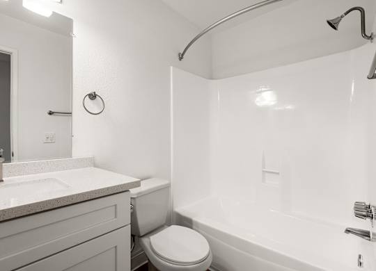 A white bathroom with a toilet, sink, and bathtub.