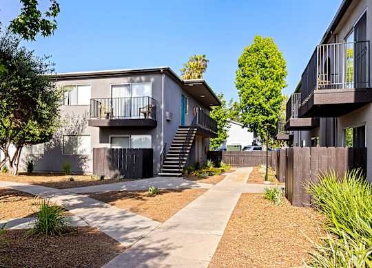 A modern apartment complex with a well-maintained garden and pathway.