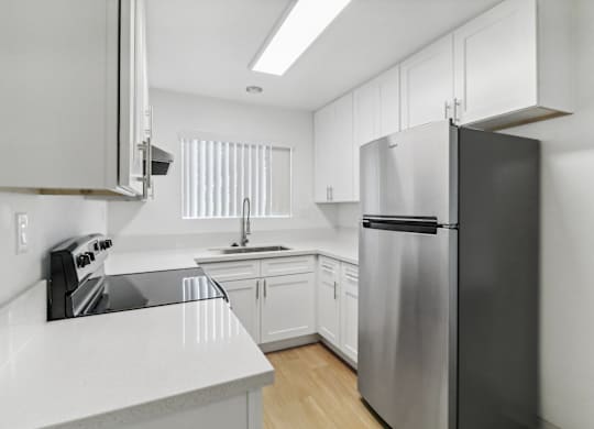A modern kitchen with a stainless steel refrigerator and white cabinets.