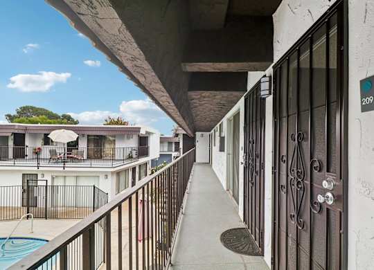 A balcony with a pool and a building in the background.