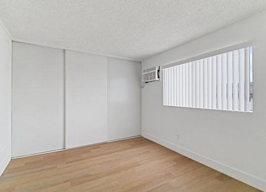 A room with a window and a wooden floor.
