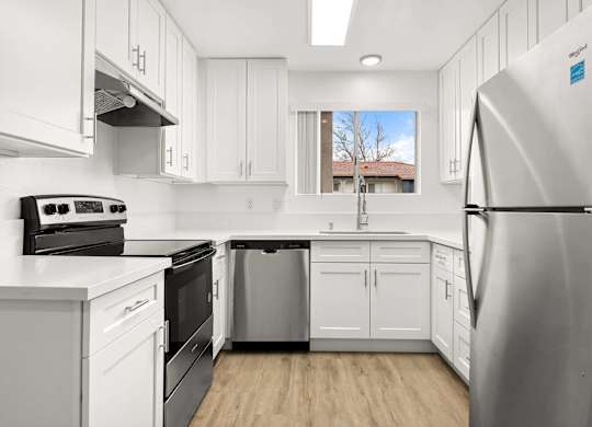A modern kitchen with white cabinets and stainless steel appliances.