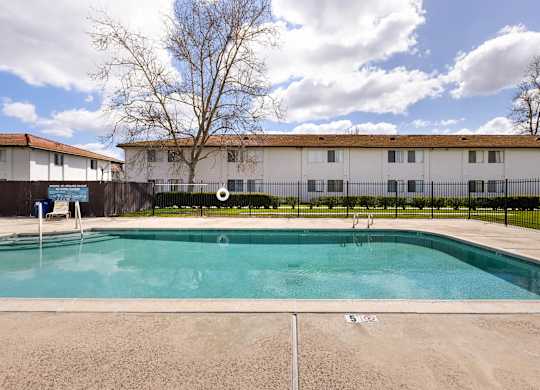 A swimming pool in front of a building with a fence around it.