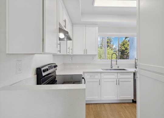 A modern kitchen with white cabinets and appliances.