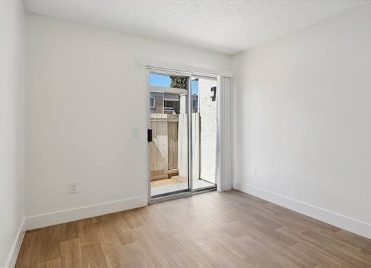 A room with a sliding glass door leading to a balcony.