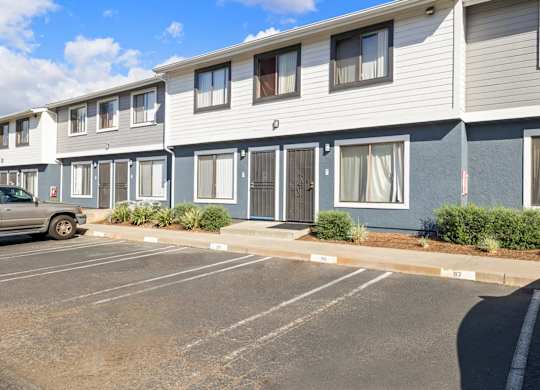 A parking lot in front of a building with grey and blue siding.