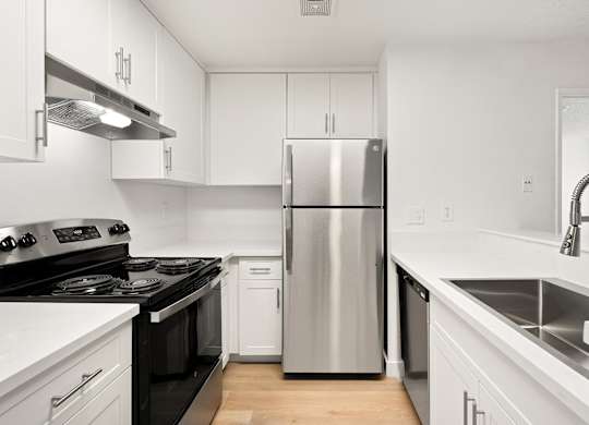 A modern kitchen with a stainless steel refrigerator and black countertops.