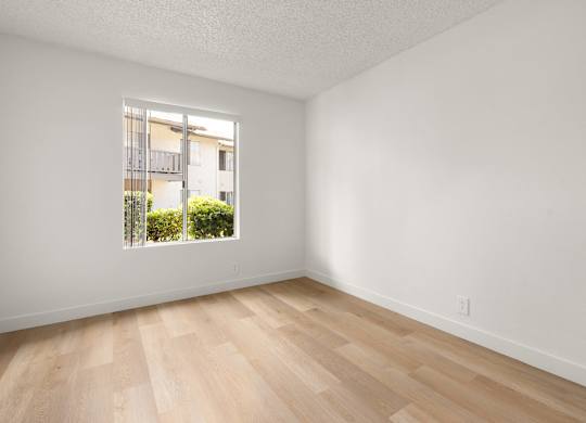 A room with a window and wooden flooring.
