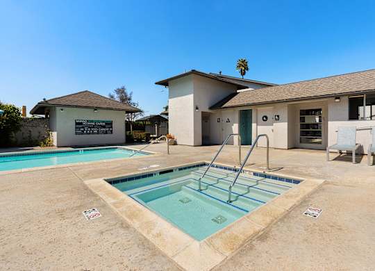 A pool with a diving board in front of a house.