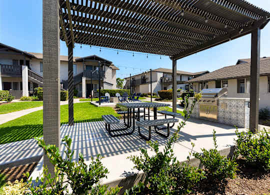 A patio with a table and chairs under a pergola.