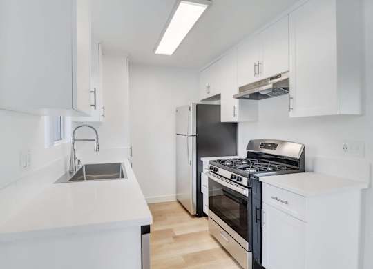 A modern kitchen with white cabinets and stainless steel appliances.