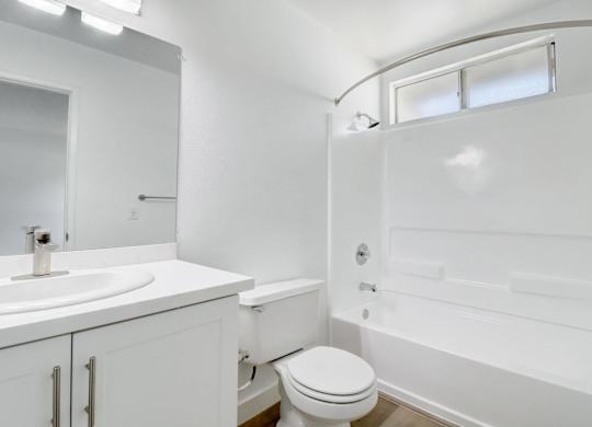 A white bathroom with a toilet, sink, and bathtub.