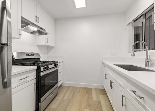 A modern kitchen with white cabinets and stainless steel appliances.