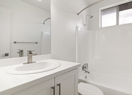 A white bathroom with a sink, toilet, and bathtub.