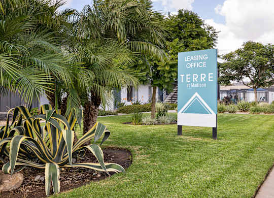 A sign for the Leasing Office at Terra Madison stands in a green lawn.