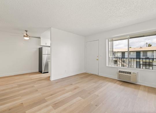 A spacious room with wooden flooring and a large window.