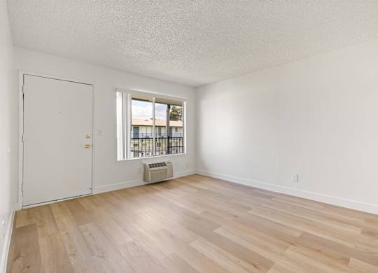 A room with a white door and a window with a view of a building outside.
