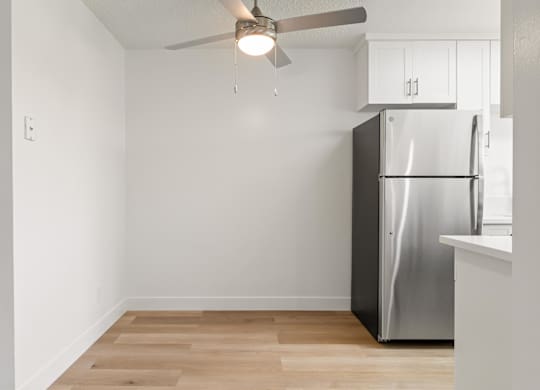 A kitchen with a refrigerator and a ceiling fan.