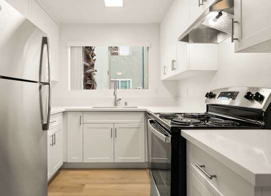 A modern kitchen with white cabinets and stainless steel appliances.