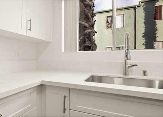 A kitchen with white cabinets and a silver sink.