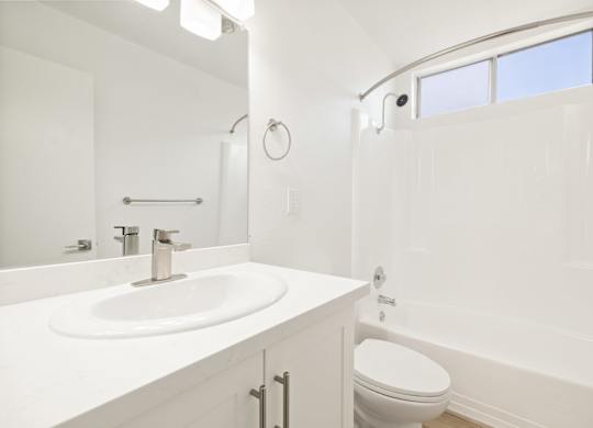 A white bathroom with a sink, toilet and tub.