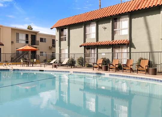 A swimming pool in front of a building with a red tile roof.