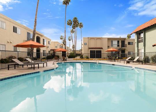 A swimming pool surrounded by palm trees and buildings.