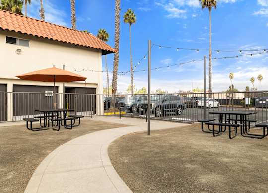 A patio area with picnic tables and a red umbrella.