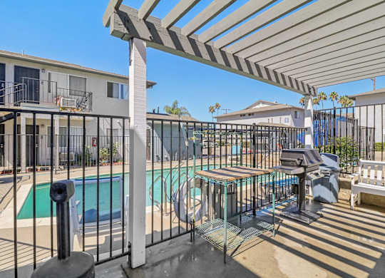 A pool area with a table and chairs under a pergola.