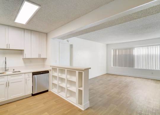 A kitchen with white cabinets and a wooden floor.
