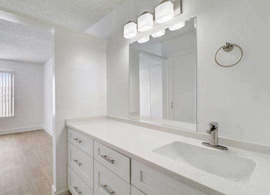 A bathroom with a sink, mirror, and lighting fixture.