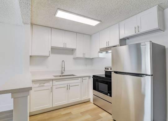 A kitchen with white cabinets and a stainless steel refrigerator.