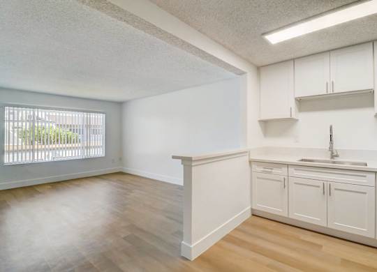 A kitchen with white cabinets and a window.