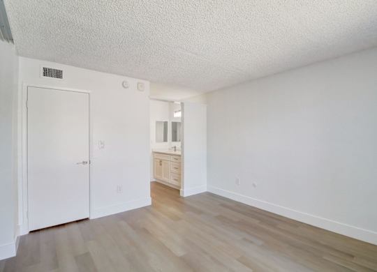 A white room with a wooden floor and a white door.