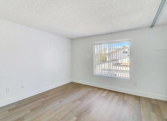 A room with a window and wooden flooring.