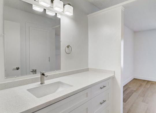 A white bathroom with a sink and mirror.