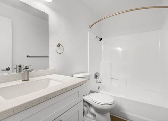 A white bathroom with a toilet, sink, and shower.