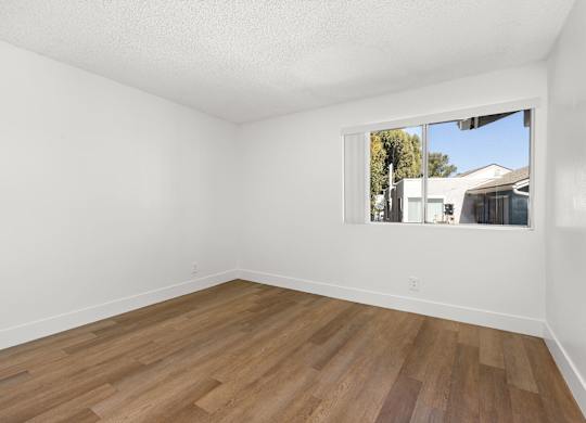 Empty room with wooden floor and a window.