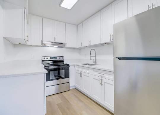 A modern kitchen with white cabinets and stainless steel appliances.