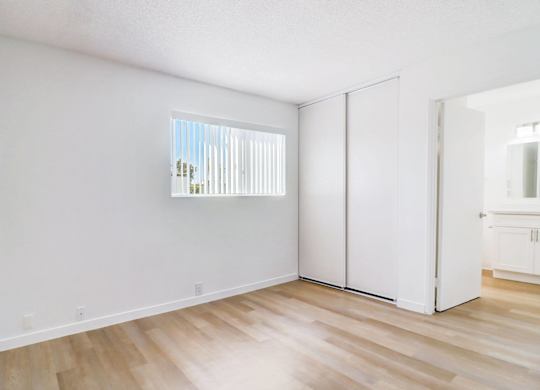 A room with a window and a wooden floor.