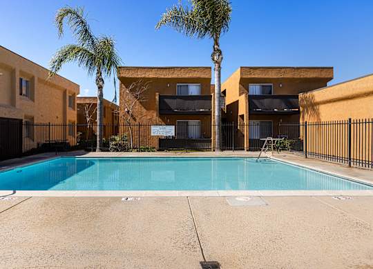 A swimming pool in front of a building with palm trees.