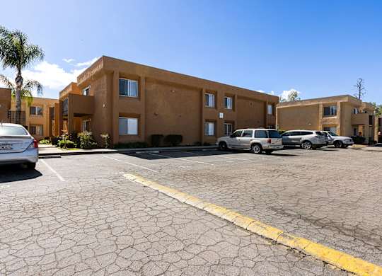 A parking lot with a building in the background and a car parked in the lot.
