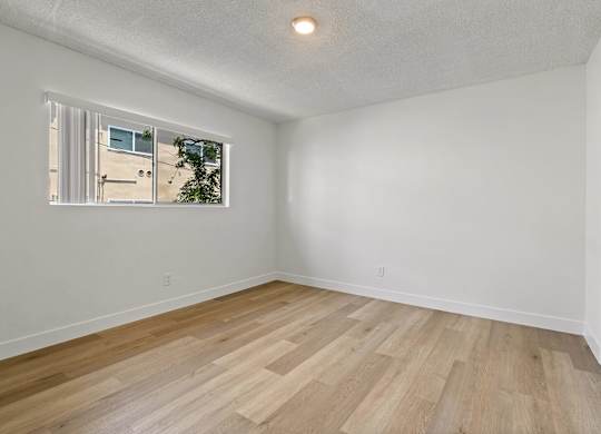 A room with a window and wooden flooring.