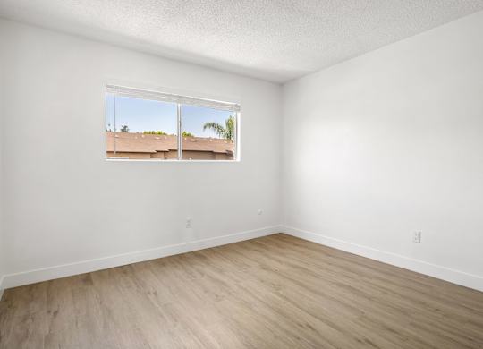 A room with a window showing a view of a building outside.