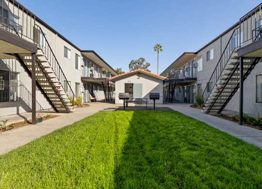 A sunny day at a residential complex with a green lawn in the foreground.