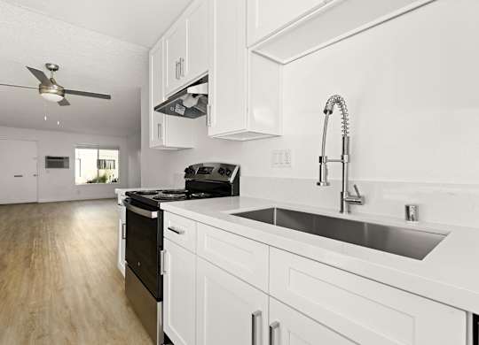 A modern kitchen with white cabinets and a black stove top oven.