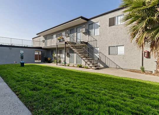 A building with a staircase and a green lawn in front.